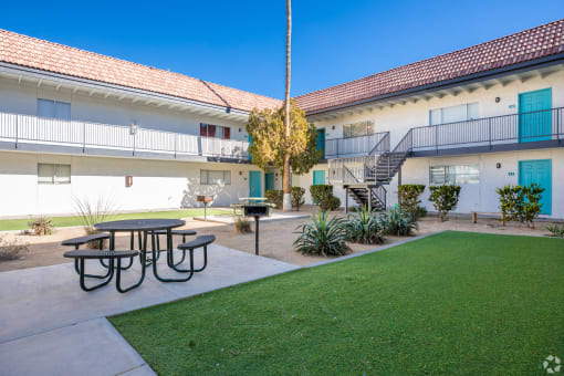 a courtyard with a picnic table and a lawn in front of a building