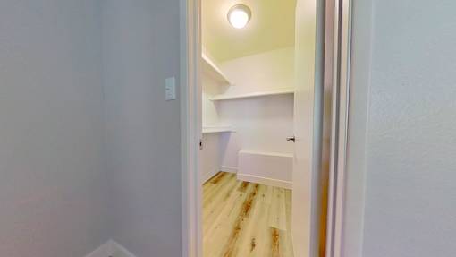 A white doorway opens to a small room with a bed and a light on the ceiling.