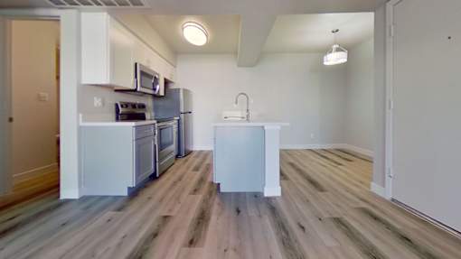 A kitchen with a white fridge and wooden floors.