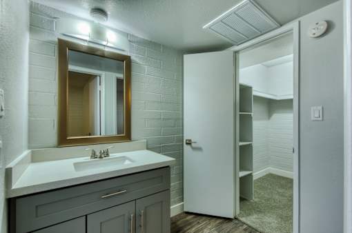 A bathroom with a sink, mirror, and a white door. at The Link Apartments, Mesa, 85201