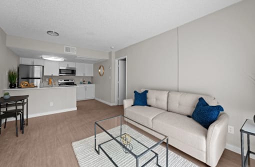 A modern living room with a white couch and a glass coffee table  at Tides on McDowell, Phoenix, 85035