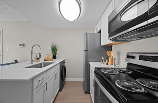 A modern kitchen with a black stove top oven and a white countertop  at Tides on McDowell, Phoenix, 85035