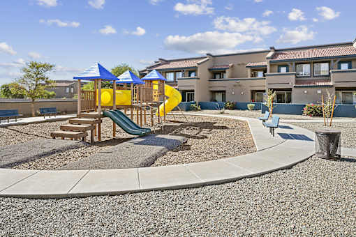 A playground with a yellow slide and a blue canopy.