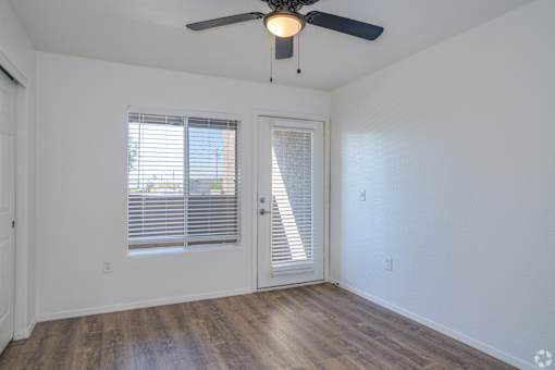 an empty living room with a ceiling fan and window