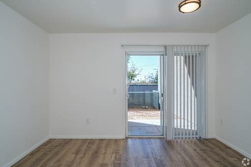 an empty living room with a sliding glass door to a backyard