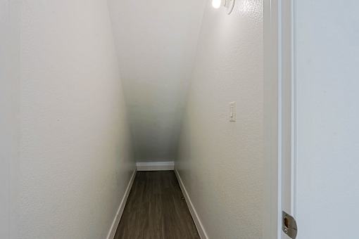 A long hallway with wood floors and white walls.