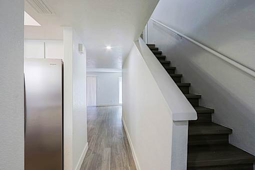 A staircase with a white railing leads to a brightly lit room.