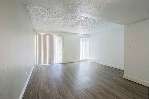 A room with wooden flooring and a window with blinds.