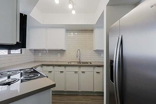 A modern kitchen with white cabinets and a stainless steel refrigerator.