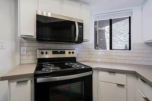 A modern kitchen with a black stove top oven and white cabinets.