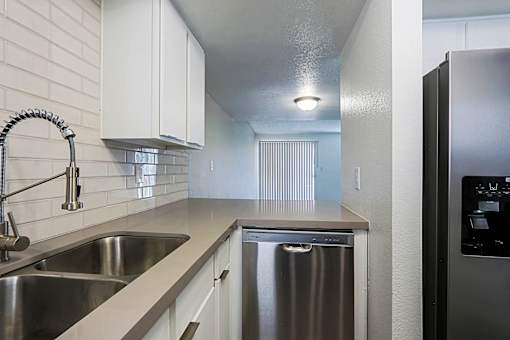 A modern kitchen with a stainless steel dishwasher and a sink.