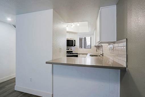 A modern kitchen with a stainless steel counter and white cabinets.