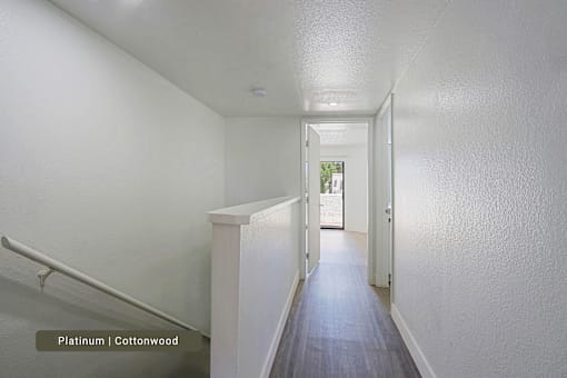 A hallway with a staircase and a door at the end.