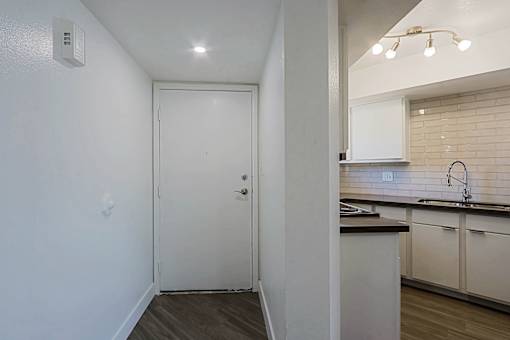 A white door in a room with a kitchen in the background.