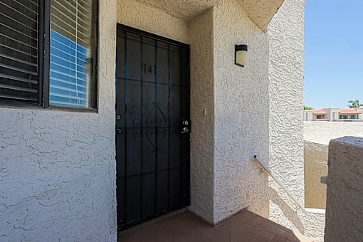 A black door with the number 141 on it is on a white wall.