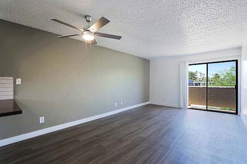 A room with a ceiling fan and sliding glass doors.