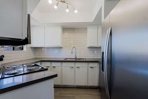 A modern kitchen with white cabinets and a black countertop.