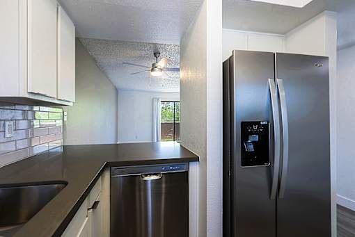 A modern kitchen with a stainless steel refrigerator and a dishwasher.