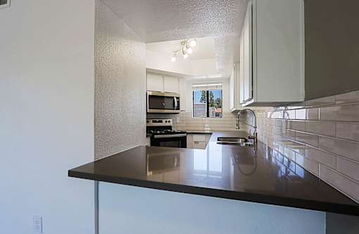 A kitchen with a black counter top and white cabinets.