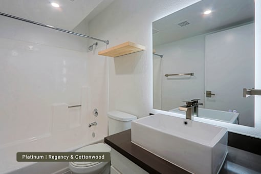 A bathroom with a backlit sink and tile tub and shower.
