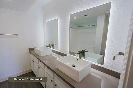 A bathroom with two sinks and a large mirror.