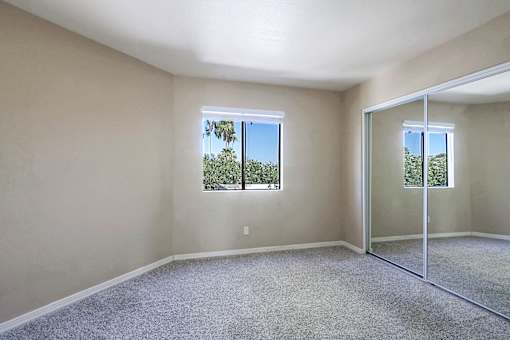 A room with a carpeted floor and a sliding glass door leading to a balcony.