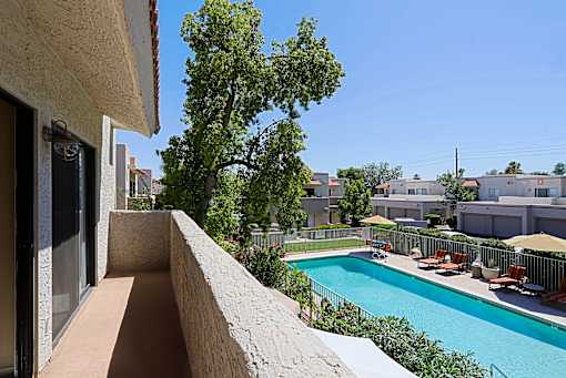 A pool with chairs and a tree in the background.