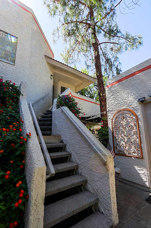 A staircase with a wooden handrail and steps leading up to a door with a decorative arch.