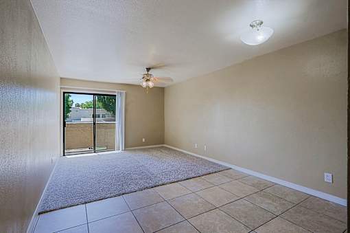 A room with a ceiling fan and sliding glass doors.