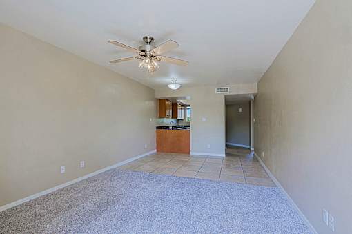 A spacious room with a ceiling fan and a carpeted floor.