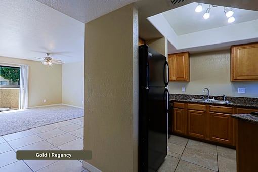 A kitchen with a black refrigerator and wooden cabinets.