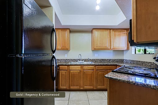 A kitchen with a black refrigerator and wooden cabinets.