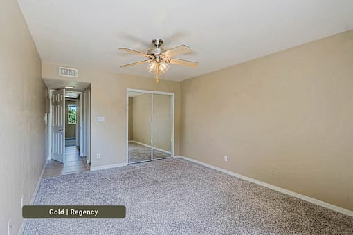 A room with a ceiling fan and a door leading to a hallway.