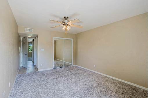A room with a ceiling fan and carpeted floor.