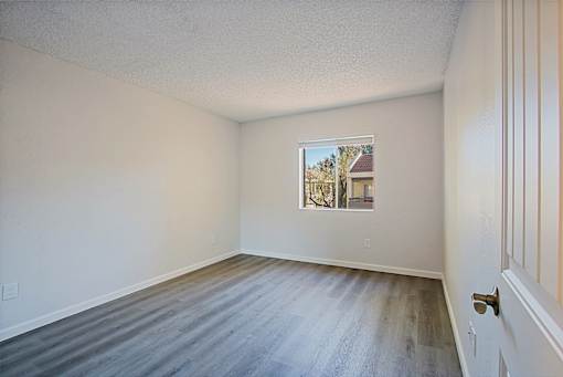 A room with a wooden floor and a picture on the wall.