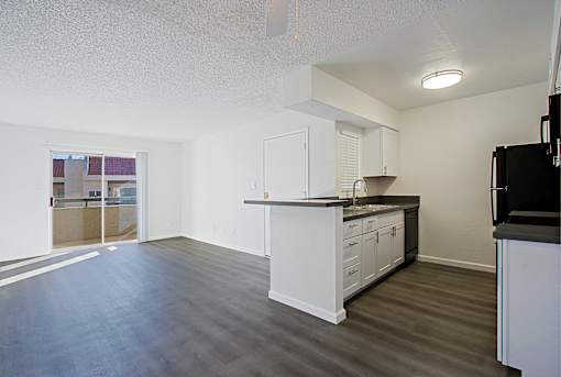 A kitchen with white cabinets and a black counter.