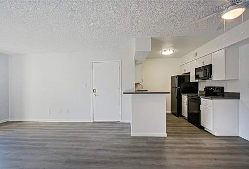 A kitchen with white cabinets and a black refrigerator.