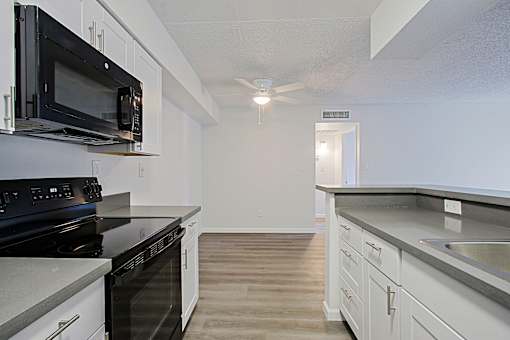 A kitchen with black appliances and white cabinets.