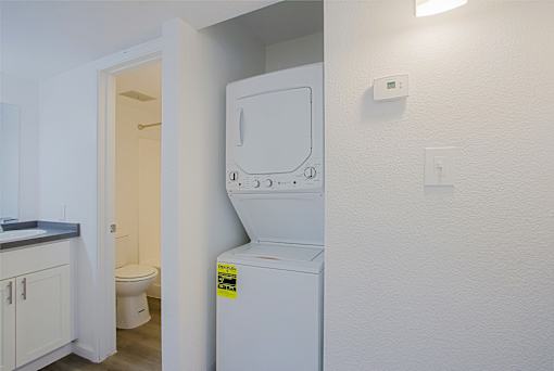 A small white washing machine is in a laundry room.