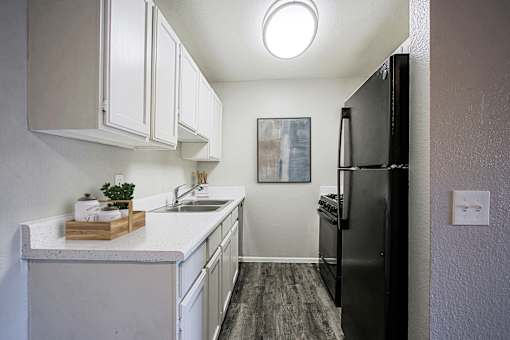 A kitchen with white cabinets and a black refrigerator.