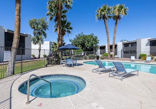 A pool surrounded by palm trees and lounge chairs.
