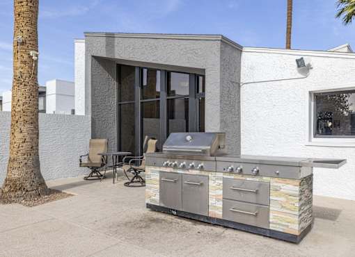 A modern outdoor kitchen with a grill and seating area.