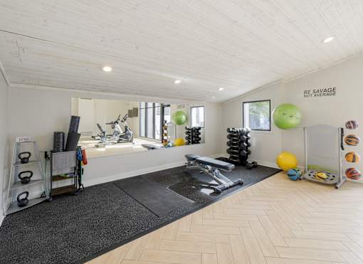 A gym with a variety of equipment including a bench press, kettlebells, and a squat rack.