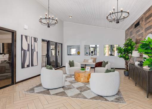 A modern living room with a white sofa set, a wooden coffee table, and a large rug.