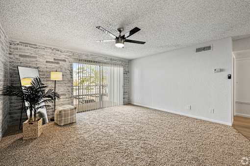 an empty living room with a ceiling fan and a window