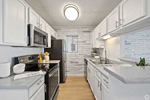 A kitchen with white cabinets and a black refrigerator.
