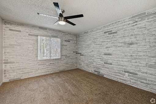 A room with a ceiling fan and a window with a white frame.