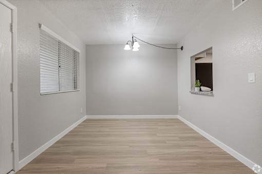 an empty living room with a window and wooden floors
