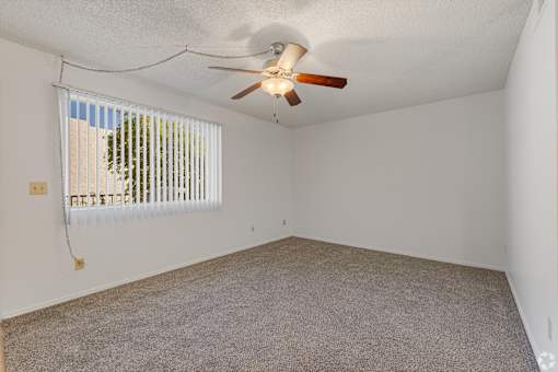 an empty living room with a ceiling fan and a window