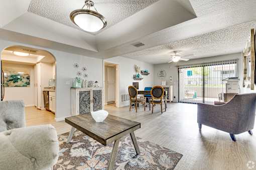 A living room with a grey couch, a coffee table, and a dining table with chairs.